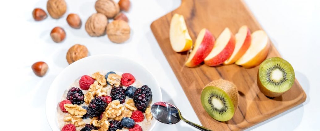 A nutritious breakfast bowl featuring fresh berries and walnuts, served with sliced fruit and kiwi.