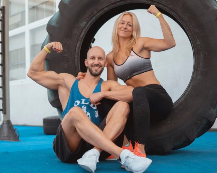 Energetic couple showing strength and fitness at the gym with a large tire.